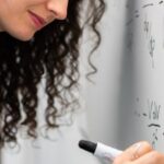 Quantum Physics - Woman Writing Formula on Whiteboard